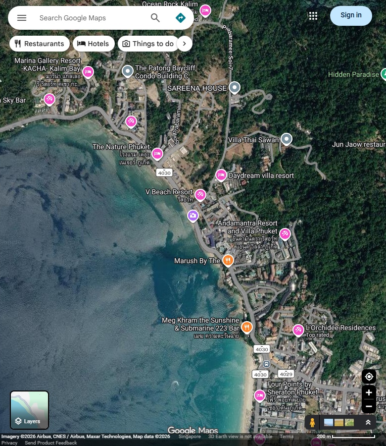 Kalim具名搜索对应的弯曲岸线、浅色水带、临海道路与岸后建筑。 Google Maps卫星图;2026-09-10查看,北向上。