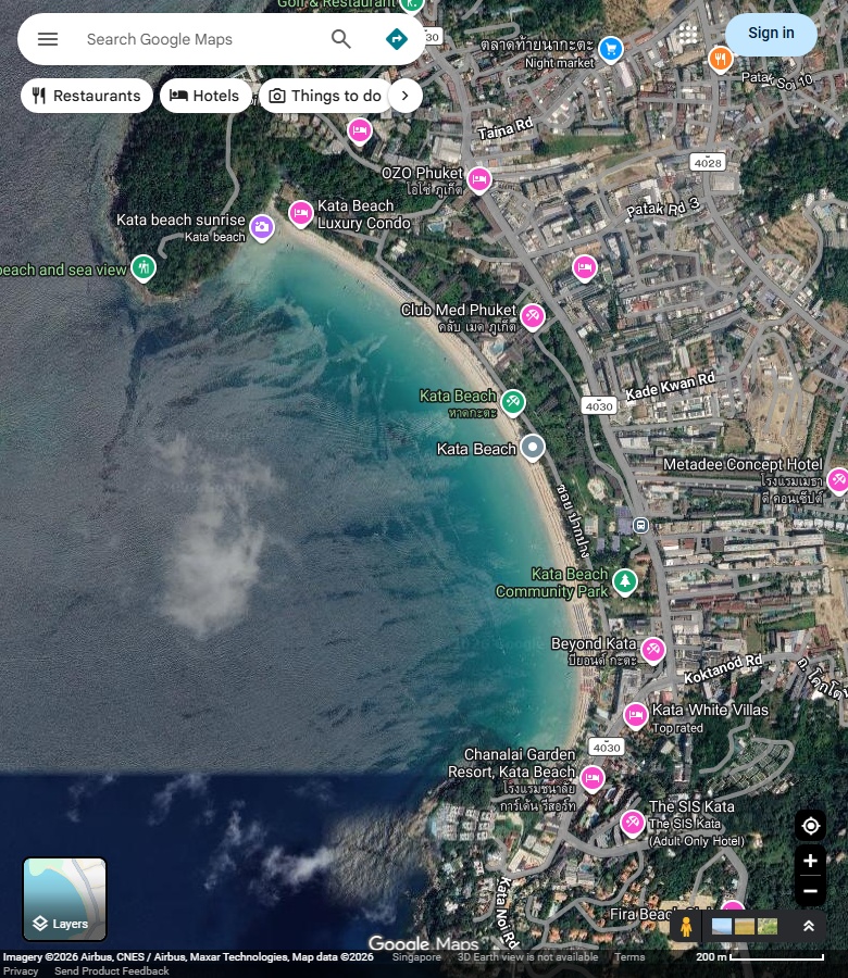 Kata主沙湾、两端岸形与岸后建筑;海面有云层和拼接色差。 Google Maps卫星图;2026-09-10查看,北向上。